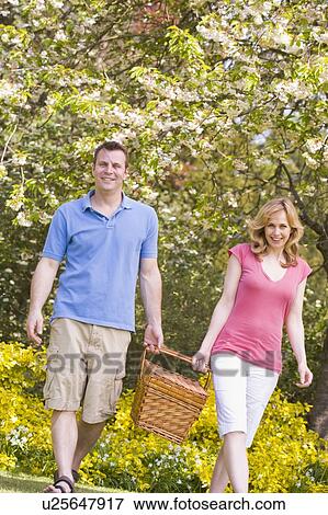 Couple walking outdoors with picnic basket smiling View Large Photo Image Stock Photo - Couple walking outdoors with picnic basket smiling. Fotosearch