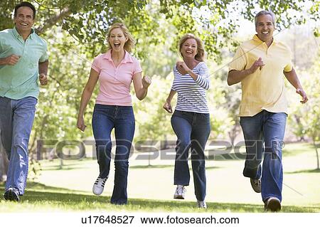 Stock Photo - Two couples running outdoors smiling. Fotosearch