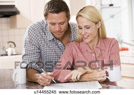 Stock Photography - Couple in kitchen with newspaper and coffee smiling. Fotosearch
