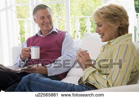 Couple in living room with coffee and newspaper smiling View Large Photo Image Stock Image - Couple in living room with coffee and newspaper smiling. Fotosearch