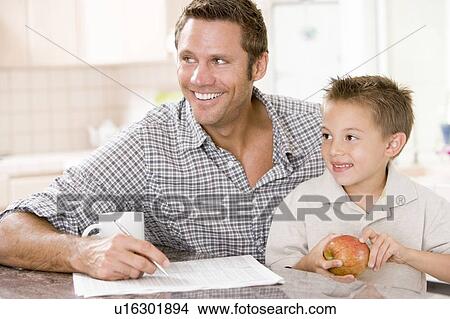 Man and young boy in kitchen with newspaper apple and coffee smiling View Large Photo Image Picture - Man and young boy in kitchen with newspaper apple and coffee smiling. Fotosearch
