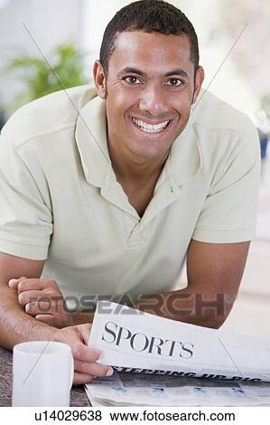 Man in kitchen reading newspaper and smiling View Large Photo Image Stock Photo - Man in kitchen reading newspaper and smiling. Fotosearch