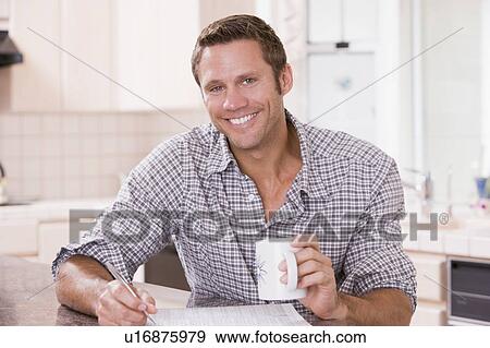 Man in kitchen reading newspaper and smiling View Large Photo Image Stock Photo - Man in kitchen reading newspaper and smiling. Fotosearch