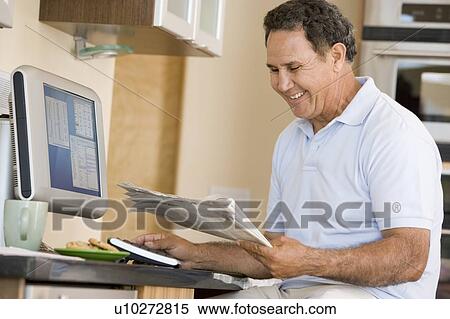 Man in kitchen with computer and newspaper smiling View Large Photo Image Stock Photography - Man in kitchen with computer and newspaper smiling. Fotosearch