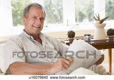 Man in living room reading newspaper smiling View Large Photo Image Stock Image - Man in living room reading newspaper smiling. Fotosearch