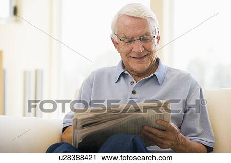 Man in living room reading newspaper smiling View Large Photo Image Stock Image - Man in living room reading newspaper smiling. Fotosearch