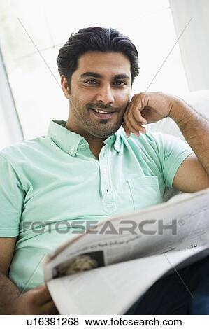 Man in living room with newspaper smiling (high key/selective focus) View Large Photo Image Stock Photo - Man in living room with newspaper smiling (high key/selective focus). Fotosearch