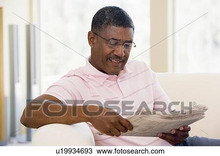 Stock Image - Man relaxing with a newspaper smiling. Fotosearch