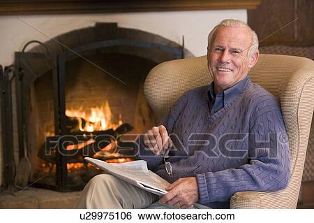 Man sitting in living room by fireplace with newspaper smiling View Large Photo Image Stock Photograph - Man sitting in living room by fireplace with newspaper smiling. Fotosearch