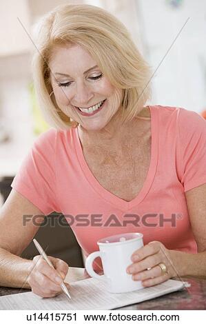 Woman in kitchen with coffee and newspaper smiling View Large Photo Image Stock Image - Woman in kitchen with coffee and newspaper smiling. Fotosearch