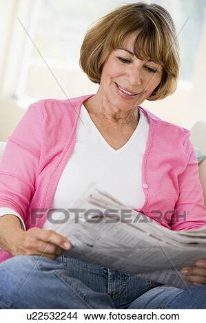 Woman in living room reading newspaper smiling View Large Photo Image Picture - Woman in living room reading newspaper smiling. Fotosearch