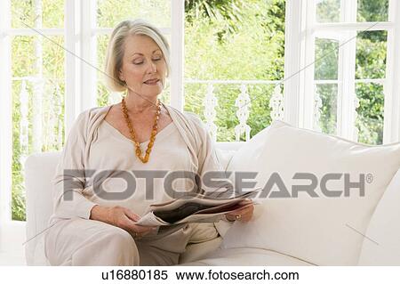 Stock Photography - Woman in living room reading newspaper. Fotosearch