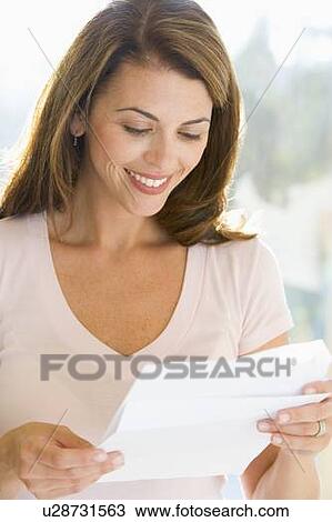 Stock Image - Woman reading letter smiling. Fotosearch