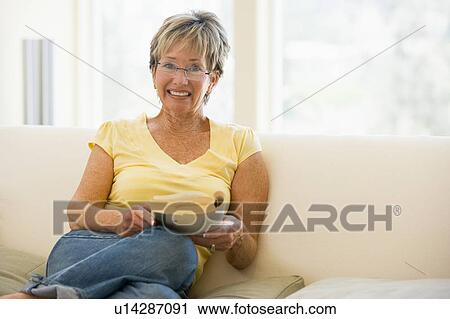 Woman relaxing with book in living room and smiling View Large Photo Image Stock Image - Woman relaxing with book in living room and smiling. Fotosearch