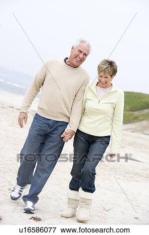 Couple at the beach holding hands and smiling View Large Photo Image Stock Photo - Couple at the beach holding hands and smiling. Fotosearch