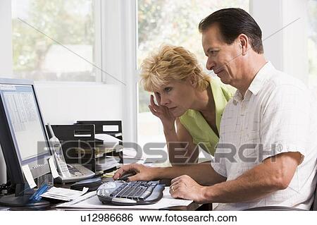 Stock Photograph - Couple in home office at computer frowning. Fotosearch