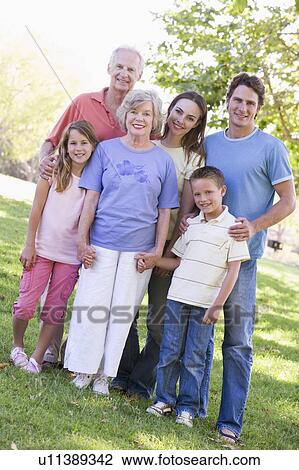 Extended family standing in park holding hands and smiling View Large Photo Image Stock Image - Extended family standing in park holding hands and smiling. Fotosearch