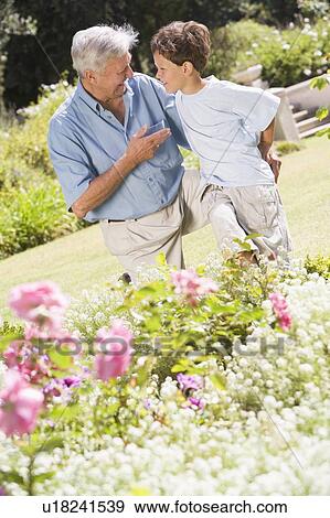 Grandfather and grandson outdoors in garden talking and smiling View Large Photo Image Stock Photo - Grandfather and grandson outdoors in garden talking and smiling. Fotosearch