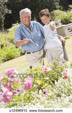 Grandfather and grandson outdoors in garden pointing at plants and smiling View Large Photo Image Stock Photography - Grandfather and grandson outdoors in garden pointing at plants and smiling. Fotosearch