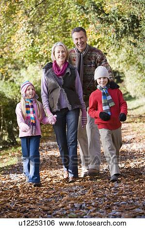 Stock Photograph - Grandparents walking with grandchildren outdoors in park and smiling. Fotosearch