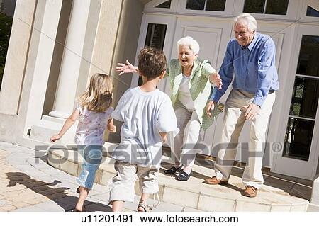 Stock Image - Grandparents welcoming grandchildren.. Fotosearch