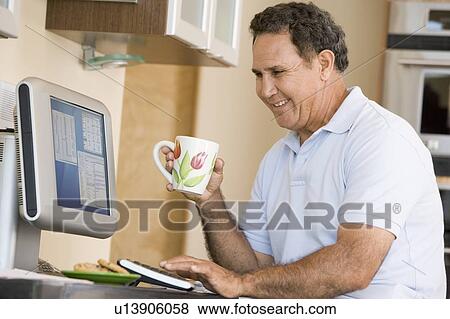 Man in kitchen with computer and coffee smiling View Large Photo Image Stock Photo - Man in kitchen with computer and coffee smiling. Fotosearch