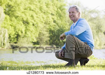 Man outdoors at park by lake smiling View Large Photo Image Stock Image - Man outdoors at park by lake smiling. Fotosearch