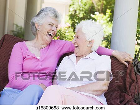 Stock Photo - Two senior women sitting outdoors on a chair. Fotosearch