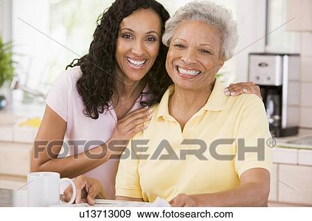 Two women in kitchen with newspaper and coffee smiling View Large Photo Image Stock Photo - Two women in kitchen with newspaper and coffee smiling. Fotosearch