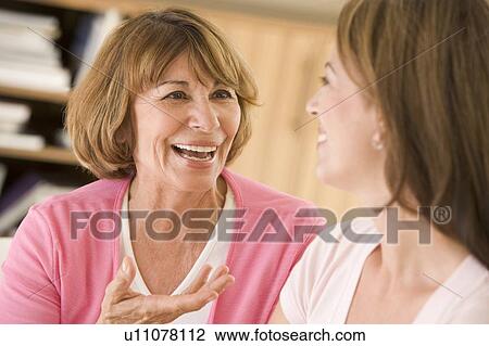 Two women sitting in living room talking and smiling View Large Photo Image Stock Image - Two women sitting in living room talking and smiling. Fotosearch
