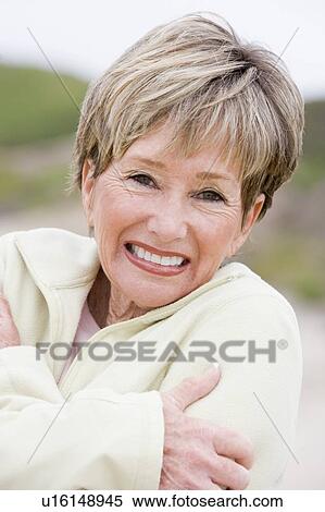 Stock Photography - Woman at the beach cold and smiling. Fotosearch