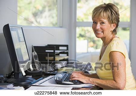 Woman in home office using computer smiling View Large Photo Image Stock Photo - Woman in home office using computer smiling. Fotosearch
