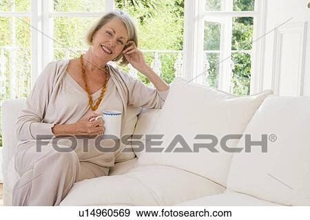 Woman in living room with coffee smiling View Large Photo Image Stock Photo - Woman in living room with coffee smiling. Fotosearch
