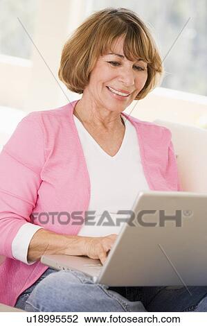 Woman in living room with laptop smiling View Large Photo Image Stock Image - Woman in living room with laptop smiling. Fotosearch