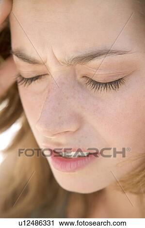 Stock Image - Head shot of woman scowling. Fotosearch