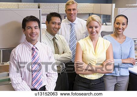 Stock Image - Business team standing in cubicle smiling. Fotosearch