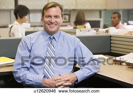Stock Photograph - Businessman in cubicle smiling. Fotosearch