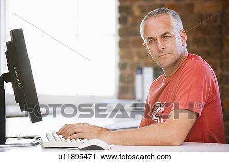 Stock Image - Businessman in office typing on computer. Fotosearch