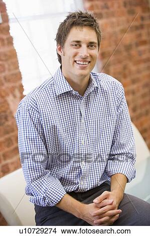 Businessman sitting in office space smiling View Large Photo Image Picture - Businessman sitting in office space smiling. Fotosearch