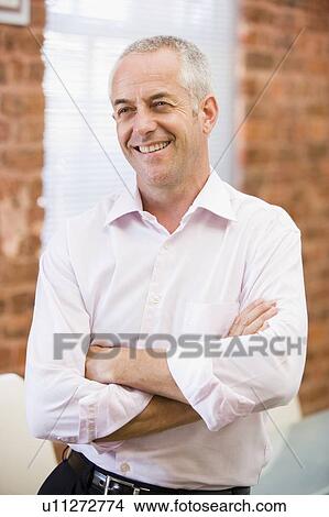 Picture - Businessman sitting in office space smiling. Fotosearch