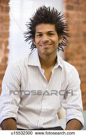 Stock Image - Businessman sitting in office space smiling. Fotosearch
