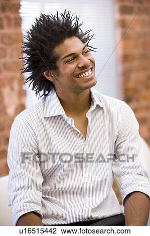 Stock Image - Businessman sitting in office space smiling. Fotosearch