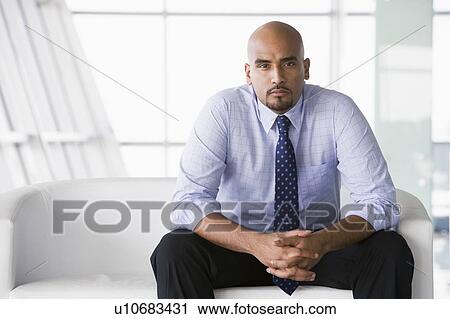 Stock Image - Businessman sitting indoors (high key/selective focus). Fotosearch