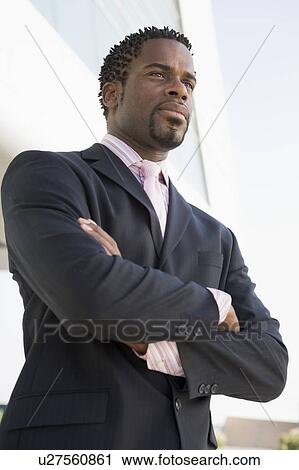 Businessman standing outdoors by building View Large Photo Image Stock Image - Businessman standing outdoors by building. Fotosearch