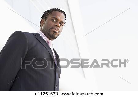 Businessman standing outdoors by building View Large Photo Image Stock Photo - Businessman standing outdoors by building. Fotosearch