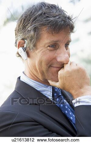 Stock Image - Businessman wearing headset outdoors. Fotosearch