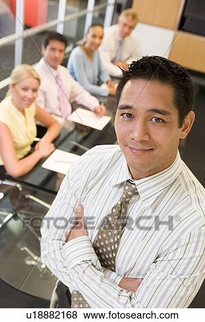 Businessman with four businesspeople at boardroom table in background View Large Photo Image Stock Photo - Businessman with four businesspeople at boardroom table in background. Fotosearch