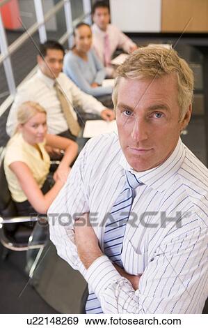 Businessman with four businesspeople at boardroom table in background View Large Photo Image Stock Photo - Businessman with four businesspeople at boardroom table in background. Fotosearch