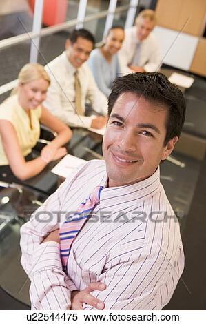 Businessman with four businesspeople at boardroom table in background View Large Photo Image Stock Photography - Businessman with four businesspeople at boardroom table in background. Fotosearch