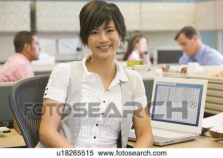 Stock Photography - Businesswoman in cubicle smiling. Fotosearch